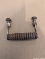 front view of wooden coil handle with metal ends and bolts