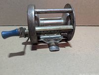 Side view showing frame, handle with blue knobs, and missing line guide