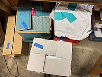 Overview of assorted boxes, plastic totes, and white poly bag