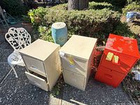 Two beige and one red filing cabinets beside white metal chair