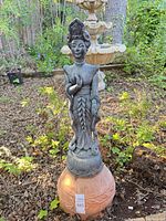 Full view of statue on terracotta base in garden setting
