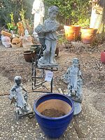Group view of three statues, blue planter, metal stand