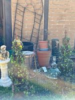 overall view of garden items grouped outside including statue, topiary plants, pots, trellises and fencing