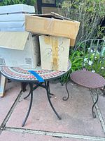 Mosaic tile table, metal chair, stacked cardboard boxes