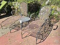 Pair of wrought iron mesh chaise lounges with side table positioned between