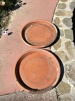 pair of round terracotta saucers on walkway