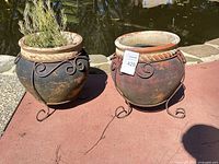 Both ceramic planters side by side showing general wear and iron stands