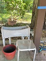 White wicker planter, red pot, side table grouped outdoors