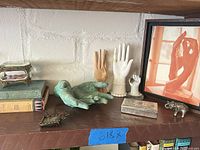 Wide view of shelf with books, hand sculptures, jewelry casket, framed art and small figurines