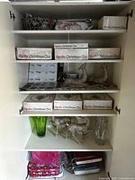 Open storage shelf showing boxed Spode dinnerware, reindeer figurines, vases, tray and other items