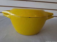 Side view of yellow enameled cast iron casserole with lid on