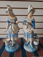 Front view of both porcelain figurines showing details of faces, dresses, accessories