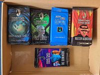 Five different sealed booster packs from various Star Trek CCG expansions inside open box