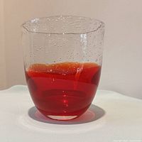 Full view of red-to-orange glass vase on white surface