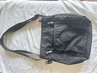 Front view of black Kipling purse showing strap, dual front zippers, logo patch