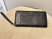 Front view of black leather Fossil wallet with wrist strap