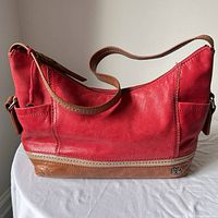 Front view of red leather The Sak purse showing caramel bottom and strap