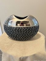 front view showing reflective silver top and textured black base