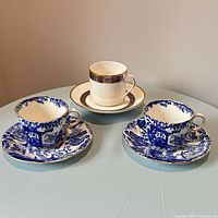 Front view of two Mikado cup-saucer sets and one Harlow cup-saucer set