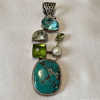 Front view showing arrangement of blue topaz, quartz, peridot, pearl and turquoise stones in sterling setting