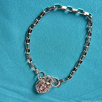 Full view of bracelet showing chain and heart clasp on blue background