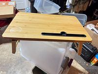 Top view of bamboo lap desk showing device slot, cup holder recess and folded legs