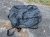 Full view of black Cabela's rooftop cargo bag on ground showing straps and logo