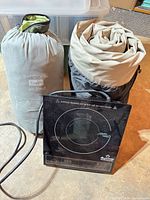 Group shot of air bed bag, sleeping bag/pad bag and Duxtop cooktop