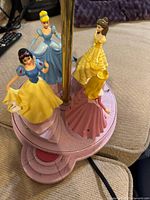 Overall view of figurine set showing four princess figures, pink base, gold pole and power cord