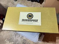 Closed gold Irishopoly box top with Notre Dame logo