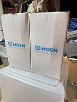 Two sealed Moen boxes containing wall sconces