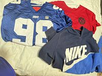 All three garments laid out: Giants jersey, Nike hoodie, Atlanta United tee