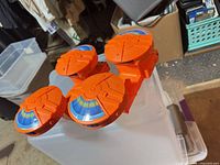 Four identical orange circular magazines on plastic bin