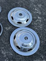 Pair of steel Champion Motorhome hubcaps on pavement, showing logos and cutouts