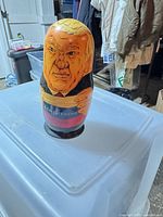 Largest nesting doll front view showing caricature painting and paint wear