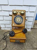 Front view showing full phone, handset, bells, dial, wood body, lower compartment