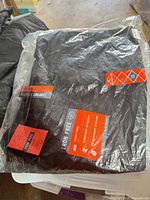 Pants sealed in clear plastic showing black fabric and labels