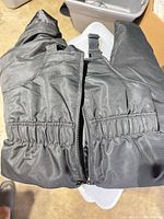 Front view of one black snow bib showing zipper and elastic waist