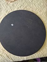 Top view of black circular balance board on quilted surface