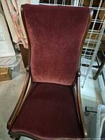 Front view of vintage rocking chair showing burgundy velvet upholstery and wooden frame