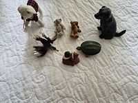 All seven animal toys and figurines arranged on quilted surface