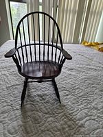 Front angle of miniature wooden rocking chair showing overall design and condition