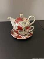 Teapot stacked on teacup over saucer displaying pattern and gold accents