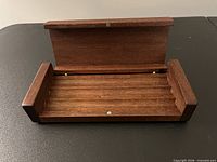 open wooden pen case showing interior grooves and brass pins