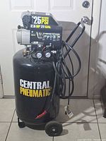 Front view of Central Pneumatic 21-gallon air compressor showing tank, handle, wheels, gauges and hose