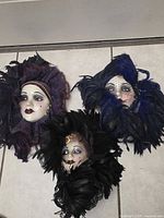 All three signed porcelain feather masks on floor