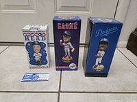 Front view of all three boxed bobbleheads and ticket insert