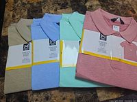 Four folded polo shirts in packaging showing colours and labels