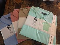 Four folded polo shirts with packaging showing colours and size S strip