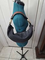 Front view of black pebbled leather Gucci hobo on mannequin, showing crescent shape
